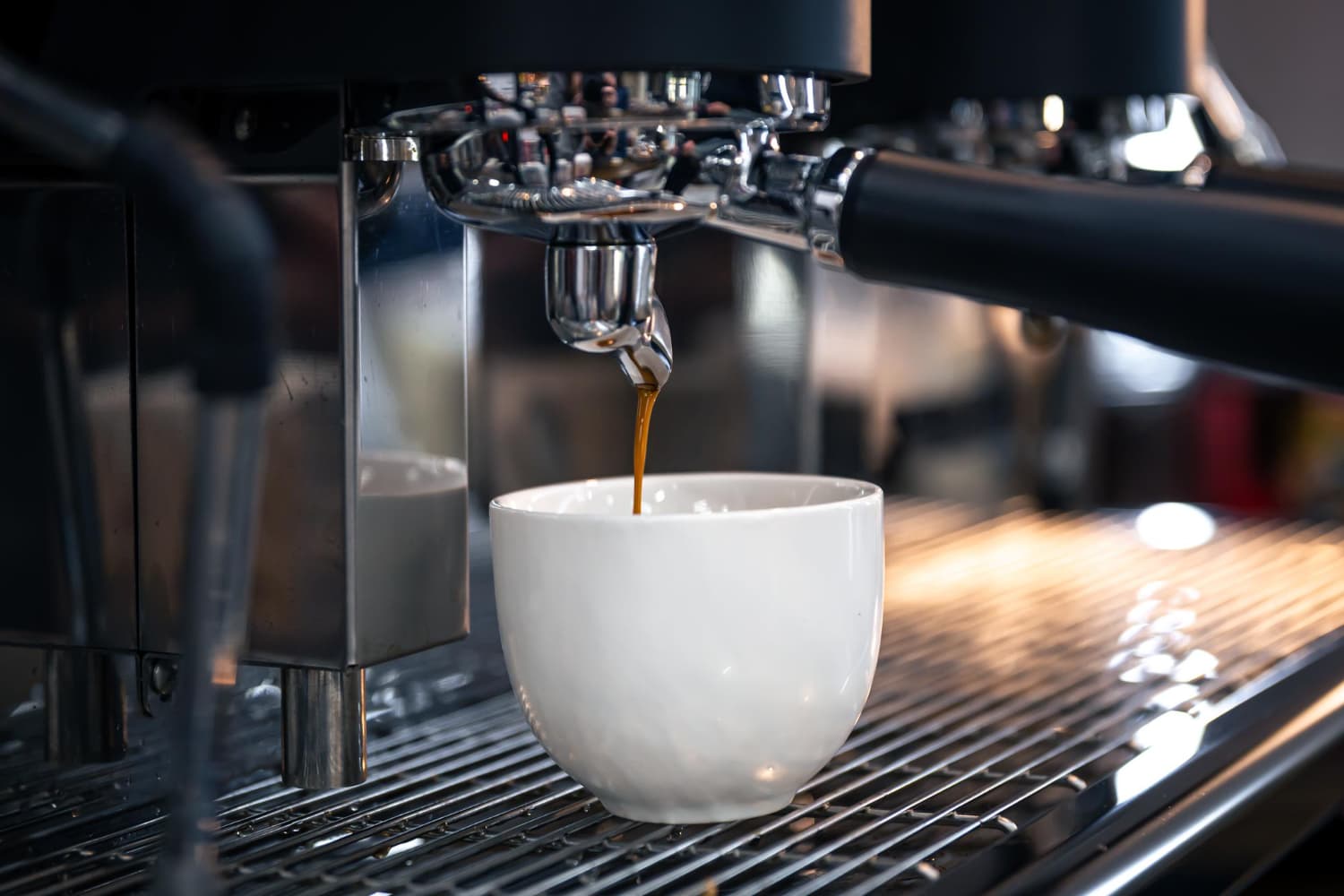 A professional barista performing water maintenance on a commercial espresso machine.