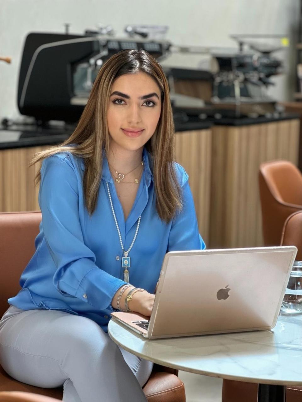 Maryam Tabatabaei, SCA Coffee Sustainability Program Trainer in the UAE, working on a laptop in a Dubai coffee bar
